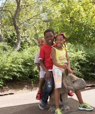 Children sitting on the rhino bronze statue