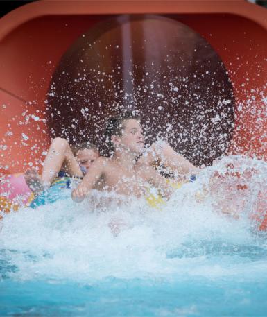 two people in a float exiting a tube slide