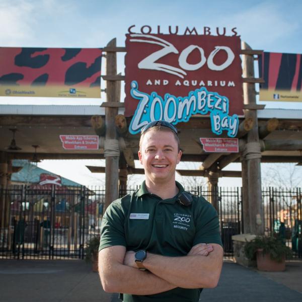 A security team member is standing in front of the Columbus Zoo and Aquarium sign at the front gate